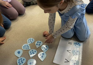 Dziewczynka dopasowuje odpowiednia ilość kropel na kartce