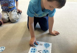 Chłopiec dopasowuje odpowiednia ilość kropel na kartce