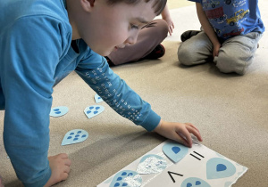 Chłopiec dopasowuje odpowiednia ilość kropel na kartce