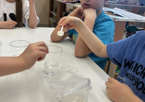 Doświadczenie "Co rozpuszcza się w wodzie?" - chłopiec nasypuje mąkę