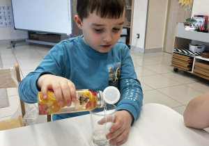 Doświadczenie "Co rozpuszcza się w wodzie?" - chłopiec nalewa olej