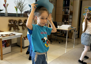 Chłopiec trzyma nad głową niebieską kartkę