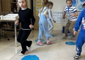 Dzieci chodzą wokół niebieskich kartek