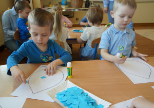 chłopcy wyklejają niebieskim papierem krople wody