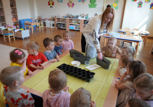 pani wsypuje ziemię do doniczki