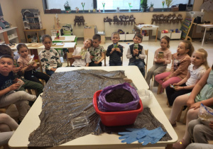 dzieci siedzą wokół stołu przygotowując się do siania owsa