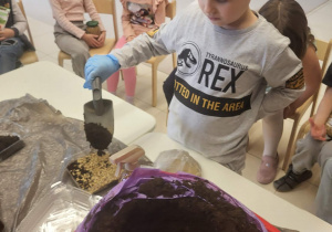 chłopiec przysypuje ziarenka owsa ziemią