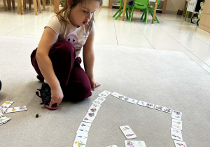 dziewczynka podczas gry domino wiosenne kwiaty układa kartę