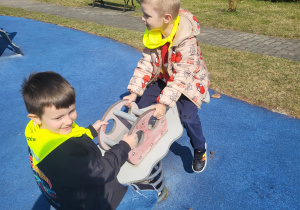 chłopcy bujają się na placu zabaw