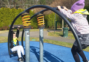 dzieci bawią się na urządzeniach terenowych