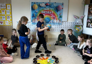 Chłopiec trzyma globus a dziewczynka rozkłada koraliki