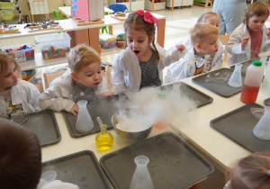 dzieci dmuchają w biła chmurę z pary