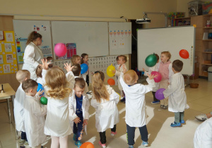 dzieci trzymają i potrząsają balonem z proszkiem w środku