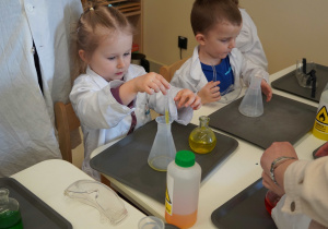 dziewczynka z a pomocą pipety nalewa odpowiedni kolor płynu