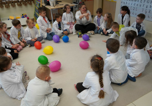 dzieci siedzą na dywanie z balonami