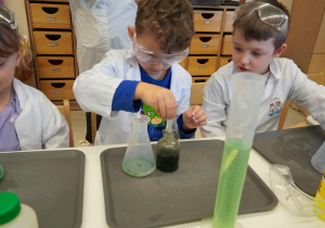 chłopiec za pomocą pipety nabiera płyn z odpowiednim kolorem