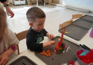 Chłopiec dekoruje swoją pracę