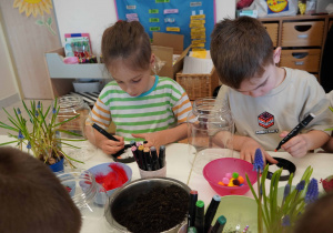 Chłopcy z precyzją kolorują gipsową figurkę