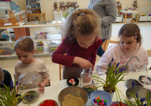 Dziewczynka nasypuje piasek do naczynia