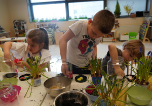 Chłopiec z wielką starannością układa piórka w słoiku