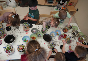 Dzieci dekorują kompozycję jajeczkami