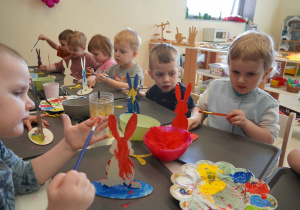 Dzieci z zaangażowaniem malują figurki