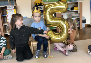 chłopiec siedzi na krześle z cyfra 5