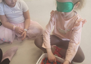 Dziewczynka odszukuje pomponiki w kolorowym makaronie