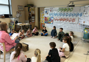 Dzieci siedzą w kole i słuchają opowiadania