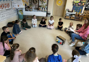 Dzieci siedzą w kole i przyglądają się "maszynie świata"