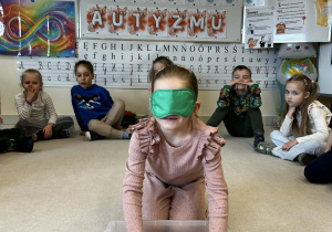 Dziewczynka z zakrytymi oczami odszukuje kulek w pudełku sensorycznym