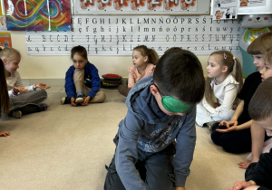 Chłopiec z zakrytymi oczami odszukuje kulek w pudełku sensorycznym