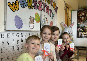 Dzieci pokazują otrzymane upominki wielkanocne z zajączkiem.