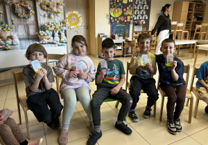 Grupa przedszkolaków prezentuje pamiątkowe prezenty świąteczne.