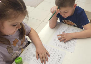 Dzieci rozwiązują wykreślankę z hasłami związanymi z Wielkanocą.