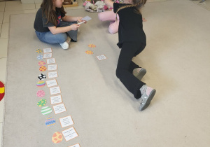 Dopasowywanie kartoników z opisem do kolorowych pisanek na dywanie.