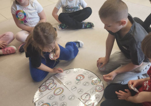 Grupa dzieci wspólnie składa edukacyjną układankę w kształcie jaja.