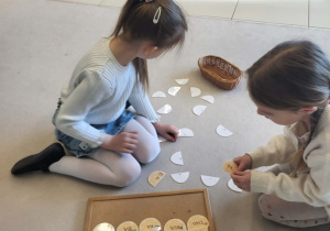 Dziewczynki składają papierowe jajka, tworząc z sylab całe wyrazy.