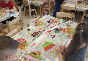 Przedszkolaki malują farbami makaronowe wzory na pisankach.