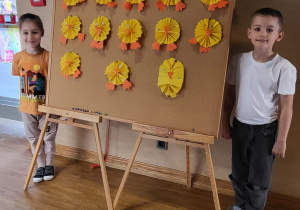 Chłopcy prezentują tablicę z pracami plastycznymi.