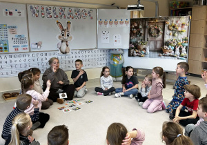 Dzieci siedzą w kole i uczestniczą w zajęciach o tradycjach wielkanocnych.