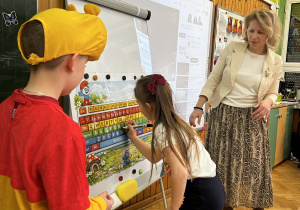 Dziewczynka zaznacza literki ze swojego imienia na tablicy sucho ścieralnej.