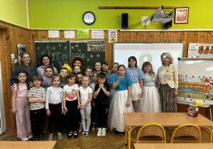 Cała grupa pozuje do wspólnego, pamiątkowego zdjęcia w udekorowanej sali lekcyjnej.