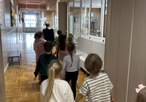 Dzieci idą parami korytarzem szkolnym.