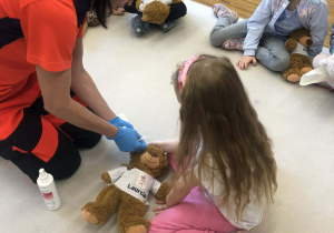 pani przykleja misiowi plaster