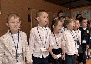 dzieci trzymaj się za ręce i słuchają