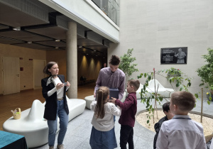 dzieci wręczają uczniowi technikum prezent i podziękowania, obok stoi pani i robi zdjęcie