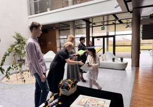 Panie dyrektor, pani od angielskiego oraz uczeń technikum stoją i gratulują dziewczynce