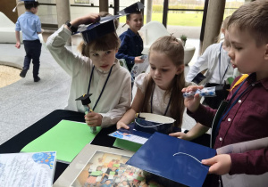 dzieci stoją przy stoliku i oglądają upominki jakie dostały