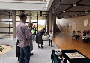 Panie dyrektor, pani od angielskiego oraz uczeń technikum stoją i gratulują chłopcu